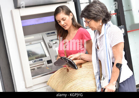 Home Pflegeperson und behinderte Frau bekommen Geld von der Bank Stockfoto