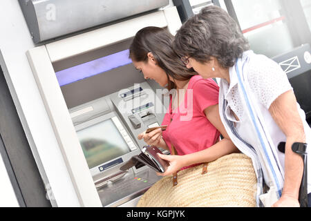 Home Pflegeperson und behinderte Frau bekommen Geld von der Bank Stockfoto