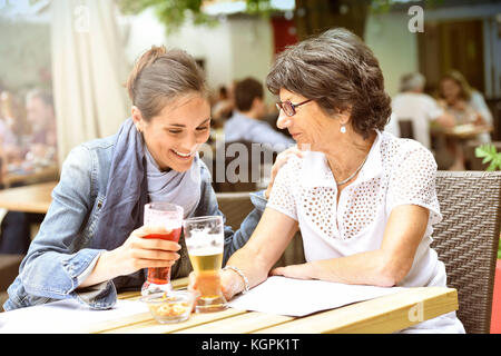 Ältere Frau und Hausfrau auf der Café-Terrasse mit dem Smartphone Stockfoto