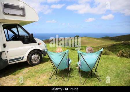 Senior paar entspannende im Camping Klappstühle, Meer Landschaft Stockfoto