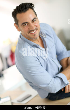 Zuversichtlich Geschäftsmann sitzen auf Schreibtisch Stockfoto