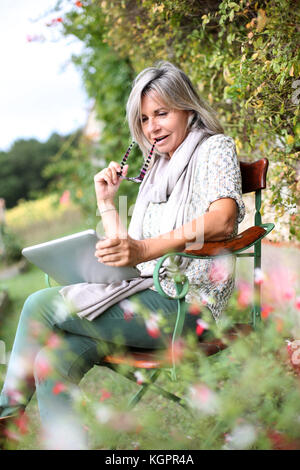 Ältere Frau mit digital-Tablette im Hausgarten Stockfoto
