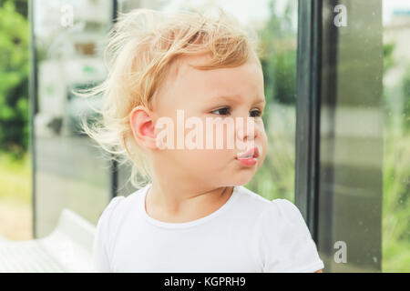 Cute kaukasischen Blonde baby girl wartet an einer Bushaltestelle. close-up Portrait Stockfoto