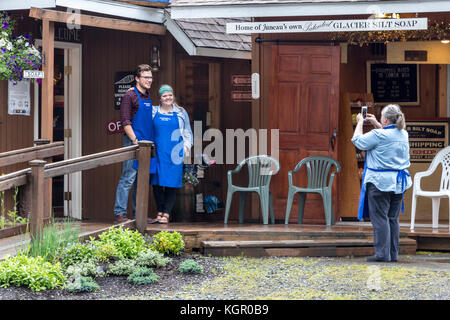 Juneau, Alaska, USA - 28. Juli 2017: Mitarbeiter der Gletscher schlick Seife shop sind die Fotos mit einem mobilen außerhalb des Speichers in einer regnerischen Tag. Stockfoto