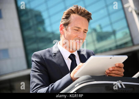 Geschäftsmann draußen Sitzen im Büro und auf Tablet Stockfoto
