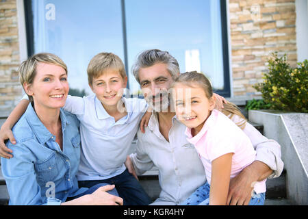 Glückliche Familie von vier vor modernen Haus sitzen Stockfoto