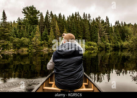 Man Kanu fahren mit dem Kanu auf dem See der beiden Flüsse in den algonquin National Park in Ontario Kanada an einem bewölkten Tag