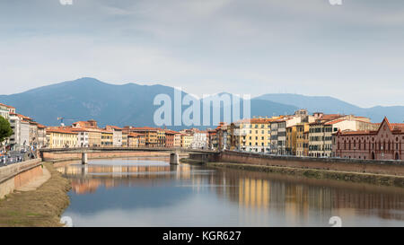 Altes Haus mit Turm mit Blick auf den Fluss Arno in Pisa, Toskana, Italien mit Apennin Berge im Hintergrund Stockfoto