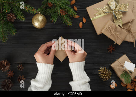 Vorbereitung Weihnachten Geschenke auf ein schwarzer Holztisch mit Tannenzweigen Stockfoto