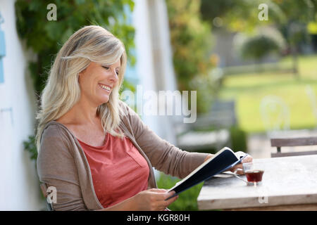 Reife Frau Lesung buchen Sie im Hinterhof Stockfoto