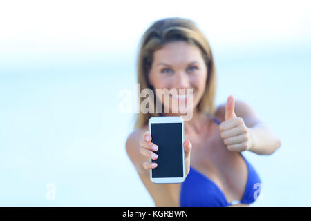 Schöne Frau im Bikini zeigen, Smartphone mit Kamera Stockfoto