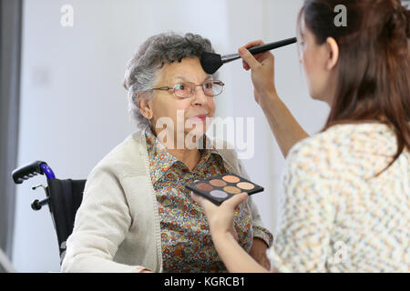 Home Pflegeperson helfen ältere Frau Make-up auf zu setzen Stockfoto