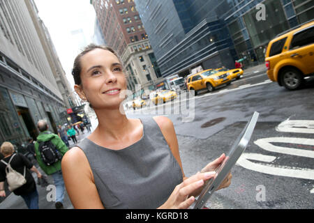 Geschäftsfrau mit Tablette für ein Taxi in New York warten Stockfoto