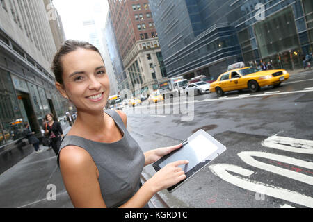 Geschäftsfrau mit Tablette für ein Taxi in New York warten Stockfoto