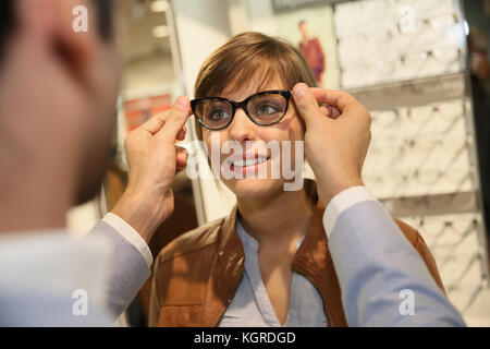 Junge Frau mit Optiker in optischen Shop versuchen, Brillen Stockfoto