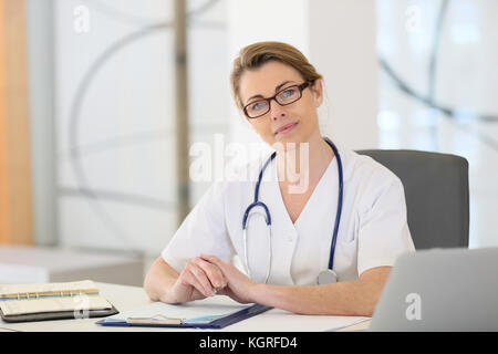 Portrait von Reife Krankenschwester am Schreibtisch im Büro sitzen Stockfoto