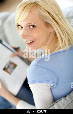 Lächelnde blonde Frau lesen Magazin Stockfoto