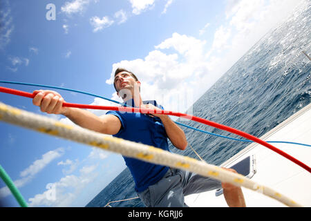 Junger Mann Anheben der Segel Katamaran während der Kreuzfahrt Stockfoto