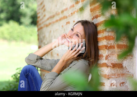 Süße Mädchen im Haus Garten, am Telefon zu sprechen Stockfoto