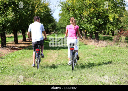 Fröhlicher junger Paare Reiten Fahrräder in der Landschaft Stockfoto