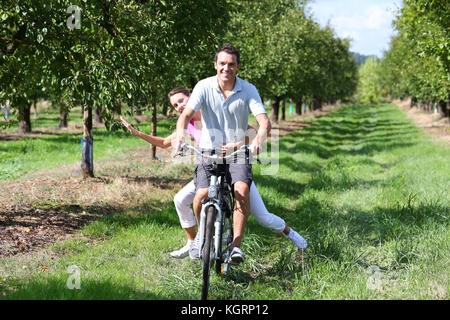 Fröhlicher junger Paare Reiten Fahrräder in der Landschaft Stockfoto