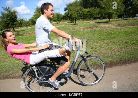 Fröhlicher junger Paare Reiten Fahrräder in der Landschaft Stockfoto