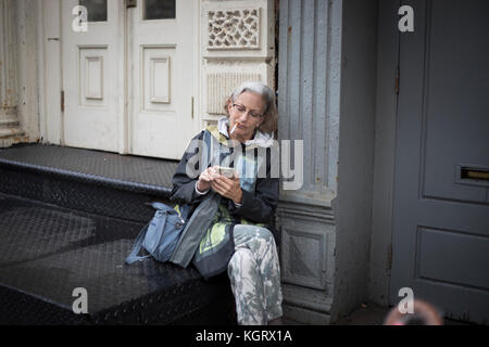 NEW YORK CITY, NY, USA - Oktober 2017 - Nicht identifizierte Frau rauchen und Ihr Handy auf die Straße. Stockfoto