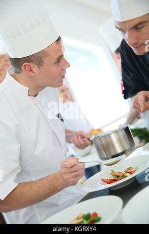 Koch mit jungen Koch in der Küche vorbereiten Dish Stockfoto