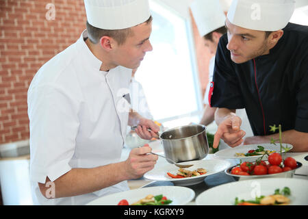 Koch mit jungen Koch in der Küche vorbereiten Dish Stockfoto