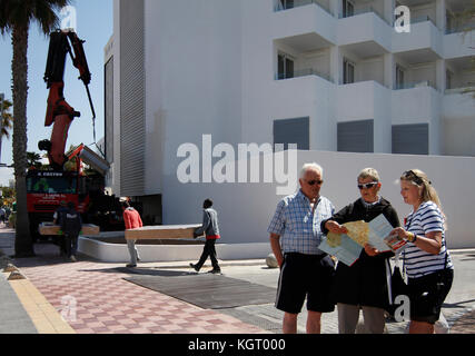 Einige Touristen Blick auf die Landkarte vor einem Hotel auf dem Strand Arenal im Frühjahr, wenn die Saison beginnt, und die Hotels bereiten Ihre Installation Stockfoto