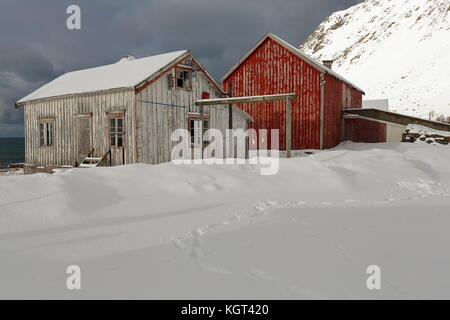 Schnee bedeckt völlig ruiniert - verlassen - Farbe verblasst Holzhütte und alten roten Häuschen am Fuße des schneebedeckten Mount hustinden neben e10 European Road. Va Stockfoto