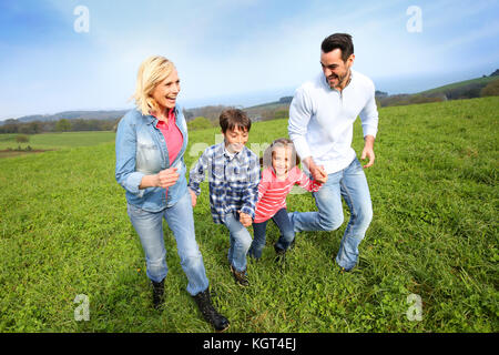 Familie von vier zusammen in natürlicher Landschaft läuft Stockfoto