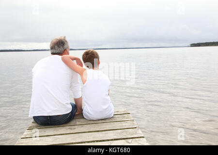 Portrait von Vater und Sohn sitzen auf einem Ponton Stockfoto