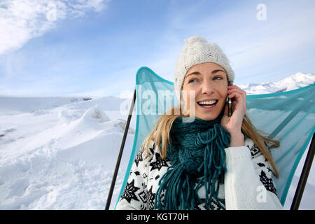 Frau in Ski Resort können Sie über Smartphone Stockfoto