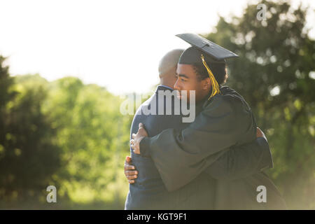 Vater seinen Sohn umarmen bei seinem Abschluss. Stockfoto