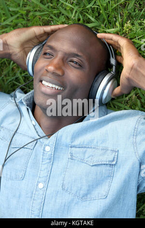 Mann zur Festlegung im Garten mit Kopfhörern Stockfoto