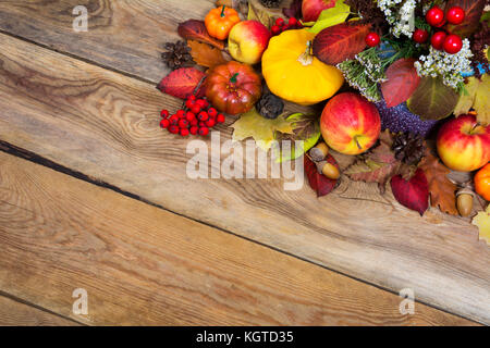 Danksagung Hintergrund mit roten Beeren, weiße Blüten, gelben Kürbis, Kürbis, Äpfel, Kegel, Eicheln, buntes Herbstlaub und Rowan auf der hölzernen t Stockfoto