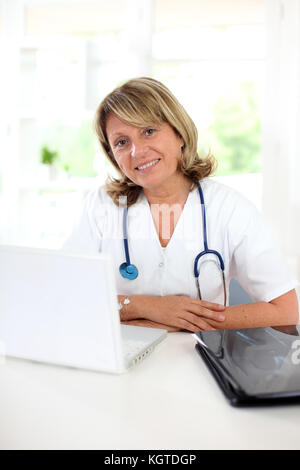 Portrait von Reife Krankenschwester an Ihrem Schreibtisch sitzen Stockfoto