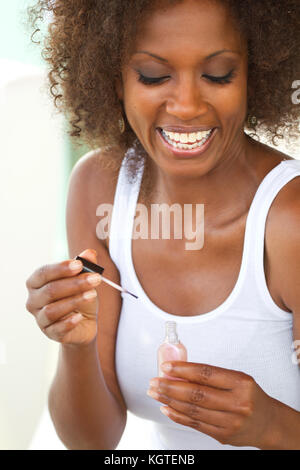 Schöne, reife Frau Anwendung Nagellack. Stockfoto