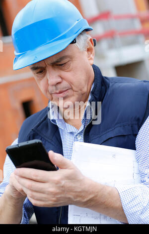 Unternehmer auf der Baustelle mit Smartphone Stockfoto