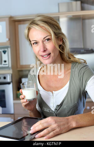 Portrait der blonden Frau trinkt Milch in der Küche zu Hause Stockfoto