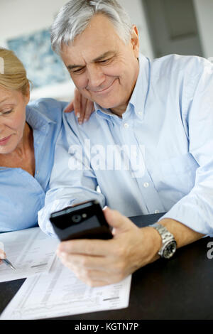 Senior Paar calculting wechseln Sie ihr Smartphone Stockfoto