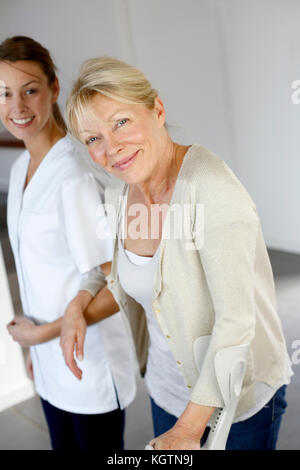 Krankenschwester helfen, alte Frau mit Krücken zu gehen Stockfoto