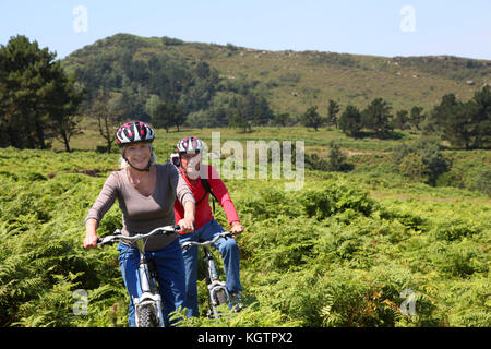 Senior paar Riding Mountain bikes in natürlicher Landschaft Stockfoto