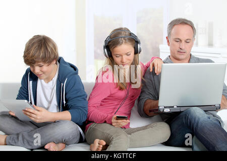 Vater und Kinder mit elektronischen Geräten zu Hause Stockfoto