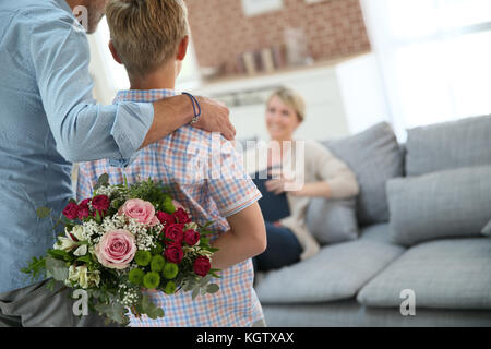 Sohn verstecken Blumenstrauß Mama am Muttertag überraschen Stockfoto