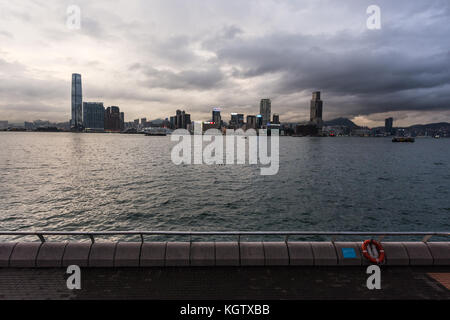 Hong Kong, China - 18. Juni 2017: die Sonne über dem Victoria Harbour und die Skyline von Kowloon in Hong Kong. Foto von der Waterfront promenad genommen Stockfoto