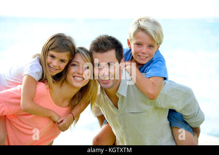 Fröhliche Eltern, die Kinder auf ihrem zurück Stockfoto