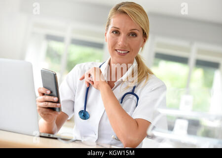 Portrait von Krankenschwester in Office mit Smartphone Stockfoto