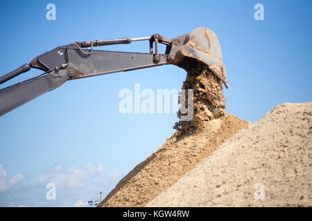 Ein großes Bügeleisen bagger Schaufel sammelt und schüttet Sand, Geröll und Steine in einem Steinbruch auf der Baustelle Straße Einrichtungen Stockfoto